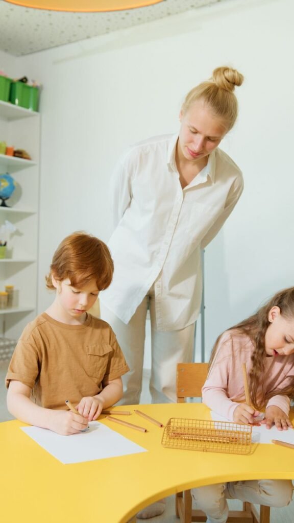 Children focus on schoolwork as a teacher oversees in a bright, modern classroom.